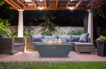 Outdoor patio with fire pit, chairs, and a pergola at night.