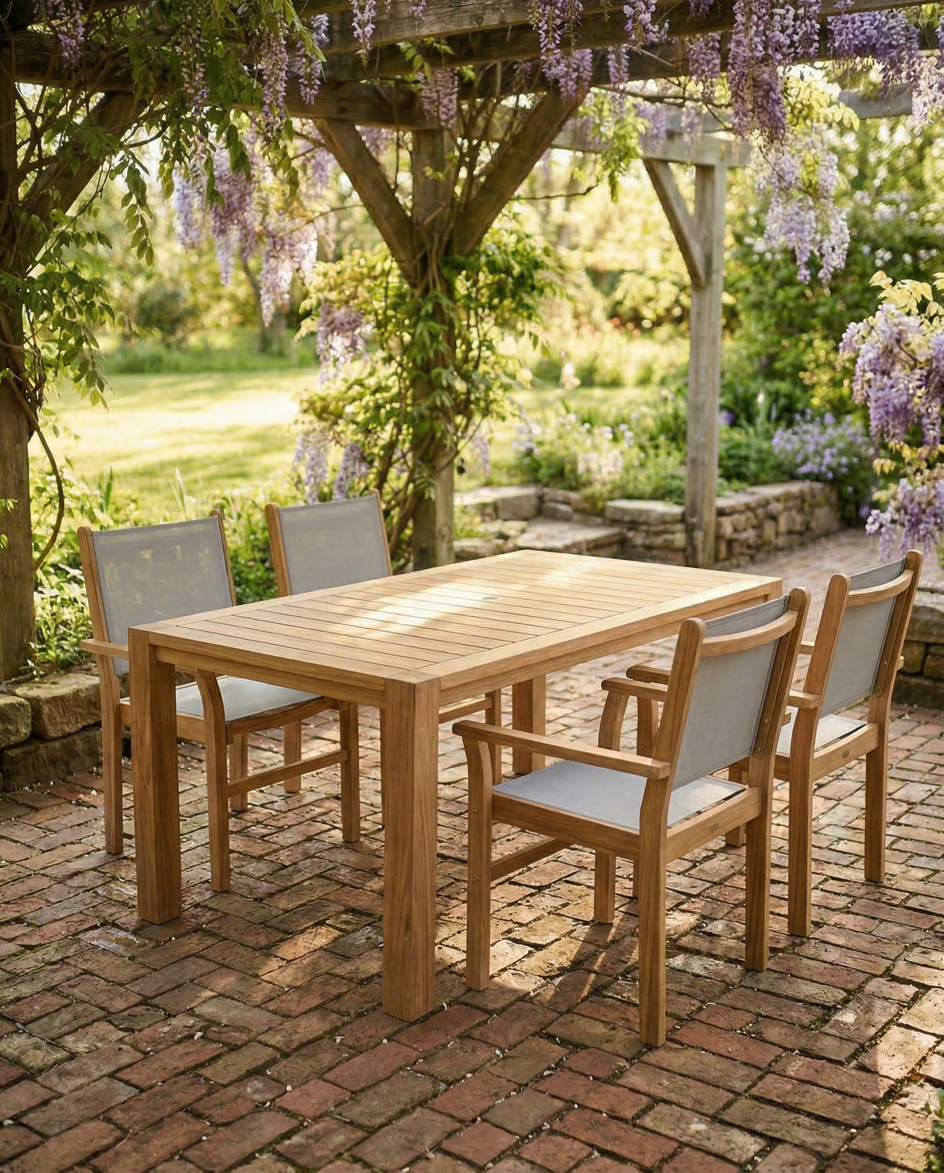 Outdoor wooden dining set with chairs on a brick patio under a wisteria-covered pergola.