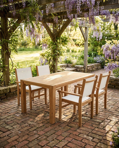 Wooden outdoor dining set with chairs under a wisteria-covered pergola.