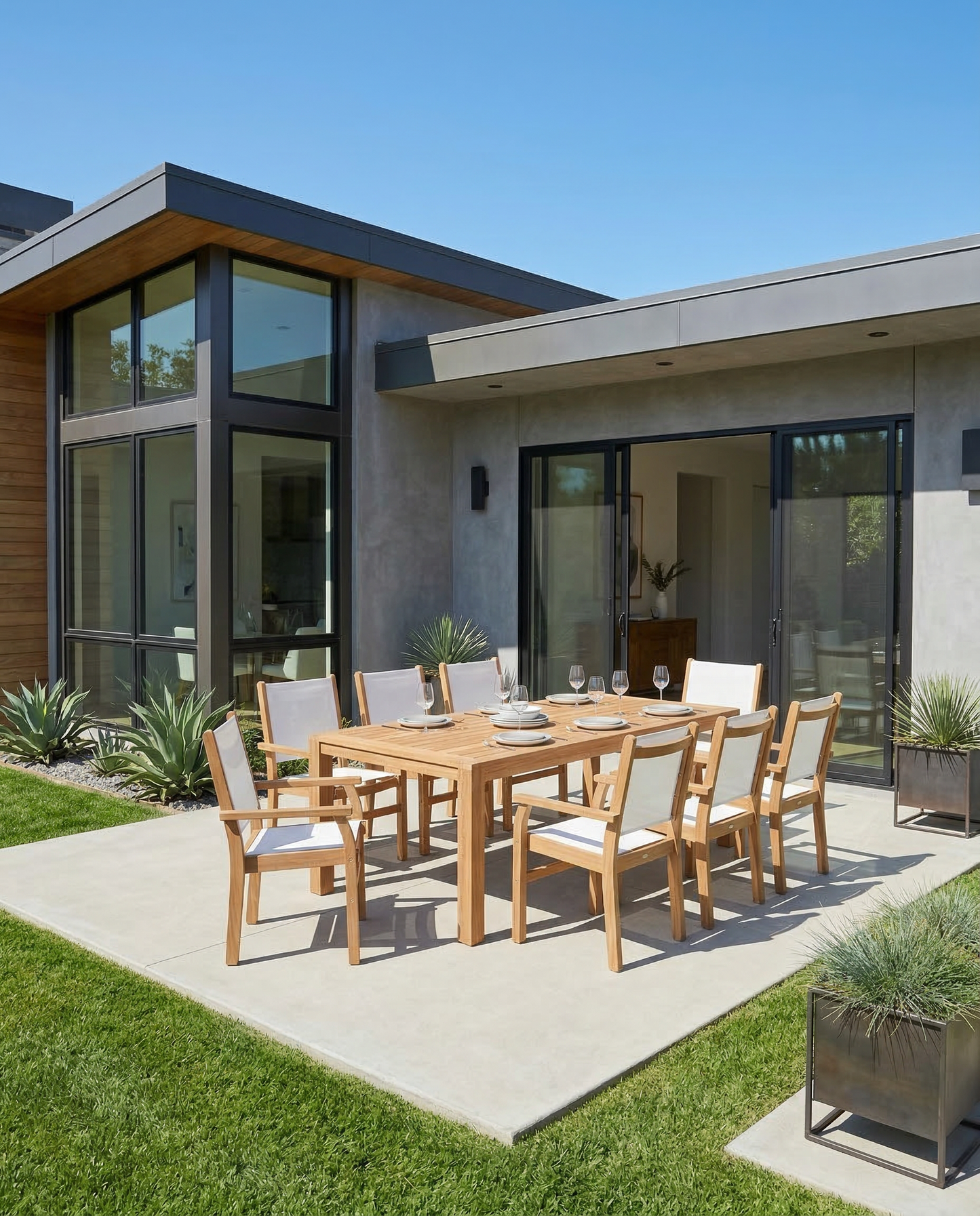 Outdoor dining area with wooden table and chairs in front of a modern house.
