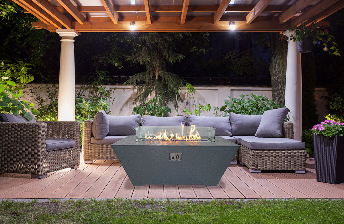 Outdoor patio with fire pit, chairs, and a pergola at night.