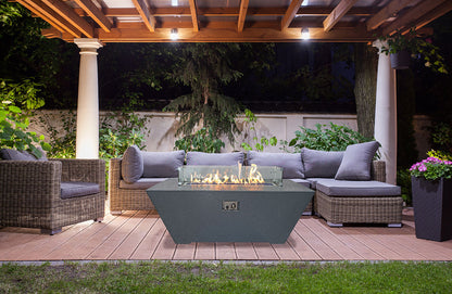 Outdoor patio with fire pit, chairs, and a pergola at night.