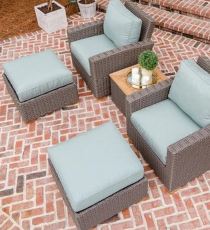 Outdoor patio furniture set with wicker chairs and ottomans on a brick patio.