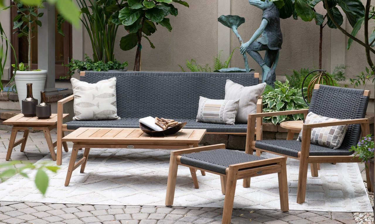 Outdoor patio furniture set with cushions and a coffee table on a stone patio.