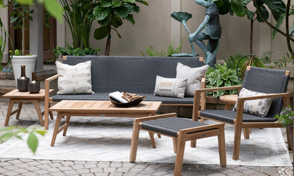 Outdoor patio furniture set with cushions and a coffee table on a stone patio.