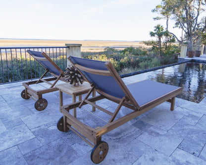Two wooden lounge chairs with blue cushions on a patio by a poolside.