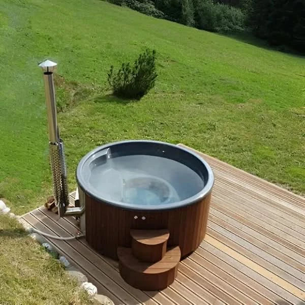 Outdoor hot tub on a wooden deck with a grassy hill in the background