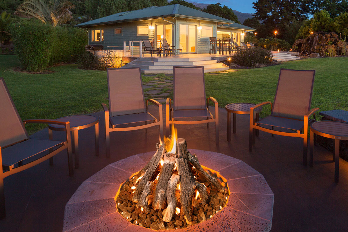 Outdoor patio with fire pit and chairs in front of a house at night.