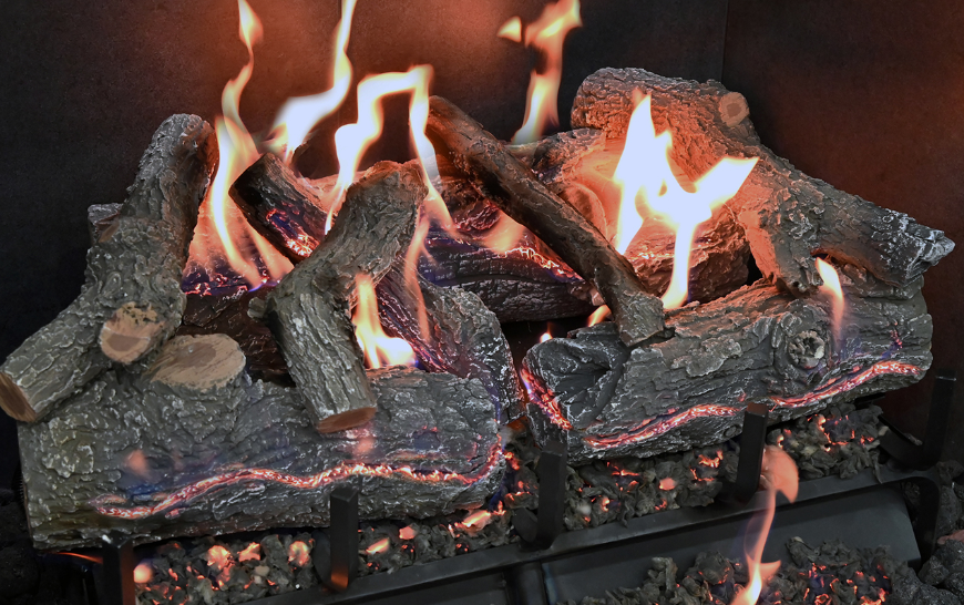 Realistic artificial fireplace logs with flames burning inside a fireplace.