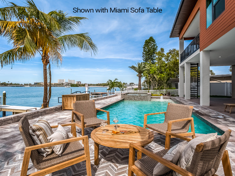 Outdoor patio with chairs, table, and pool near a house with a view of the water.
